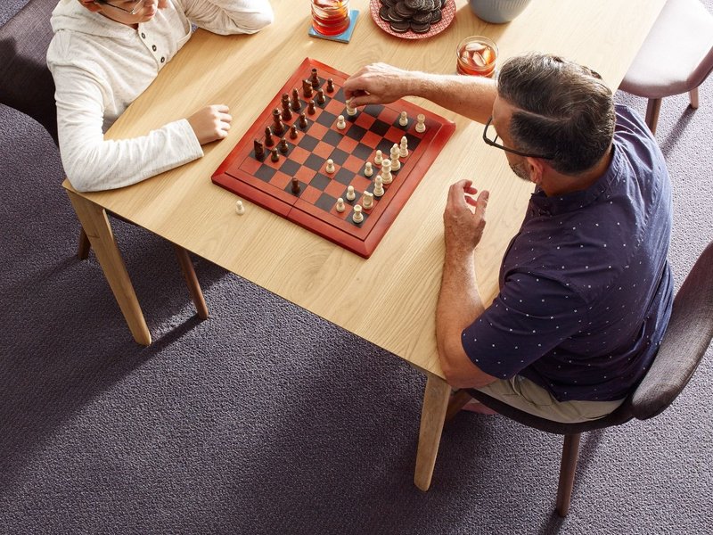 father and son playing chess and eating snacks in a living room with gray carpet by Fleeners Home Planning Inc in Leitchfield, KY